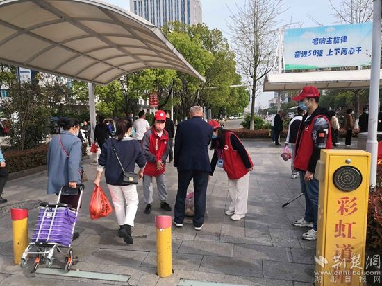志愿服務(wù)隊(duì)在人民醫(yī)院路口開展文明交通體驗(yàn)活動，并幫助老人提重物.jpg.jpg