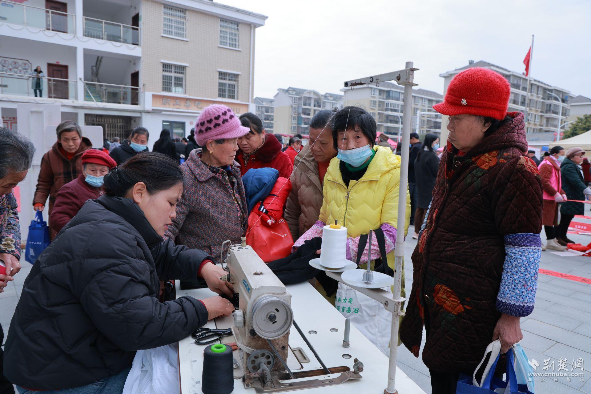 衣物縫補(bǔ)攤前，志愿者飛針走線為居民修補(bǔ)破損衣物.jpg.jpg